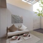 Modern seating area with decorative coral wall art, bowls, and a small tree in a serene space.