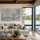 Modern living room features three abstract wall art pieces, a cozy sofa, and large windows overlooking a lake.
