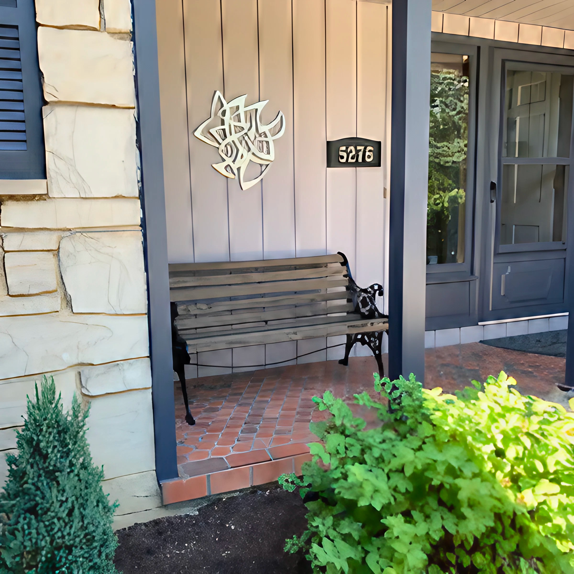A front porch features a wooden bench, decorative wall art, and house number 5276. Green plants surround the area.
