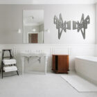 Modern bathroom featuring a freestanding sink, wooden cabinet, and decorative wall art. White towels on a rack.