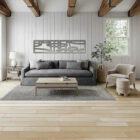 A modern living room features a gray sofa, coffee table, and decorative plants near large windows.