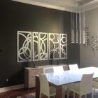 Modern dining area features a glass table, white chairs, and abstract wall art. Wine rack displayed on the wall.