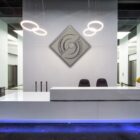 Modern reception area with a sleek white desk, two chairs, and a decorative wall feature.