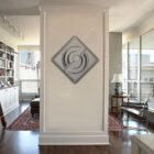 A modern, diamond-shaped display is mounted on a white wall in a bright living room.