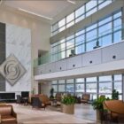 Modern lobby with large windows, decorative wall, seating areas, and indoor plants.