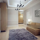 A modern hallway features a plush rug, sleek sofa, wall art, and elegant lighting fixtures.