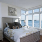 A coastal bedroom features a bed with decorative pillows and a palm tree artwork on the wall.