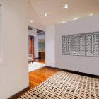 A modern hallway features abstract art, a patterned rug, and a glimpse of a living area with curtains.