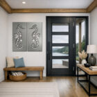 Two seahorse wall art pieces hang beside a modern entryway with a view of a river and forest.