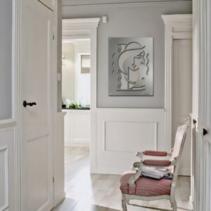 A hallway features a decorative wall art piece and a pink upholstered chair with magazines.