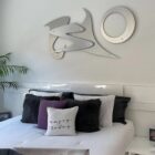 Modern bedroom with decorative wall art, plush pillows, and a potted plant beside the bed.