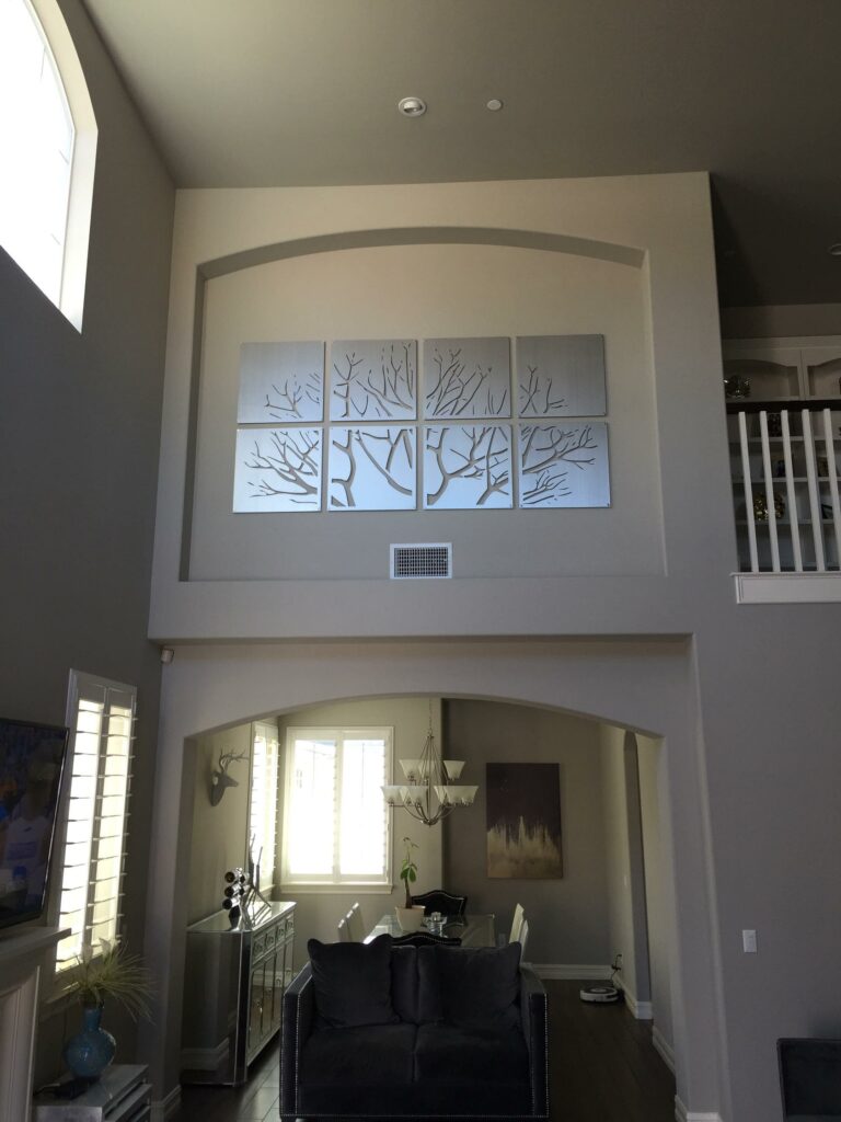 A large wall features silver tree artwork above a modern living area with a couch and dining table.