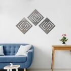 Three abstract diamond wall decorations hang above a blue sofa with cushions and a small plant on a side table.