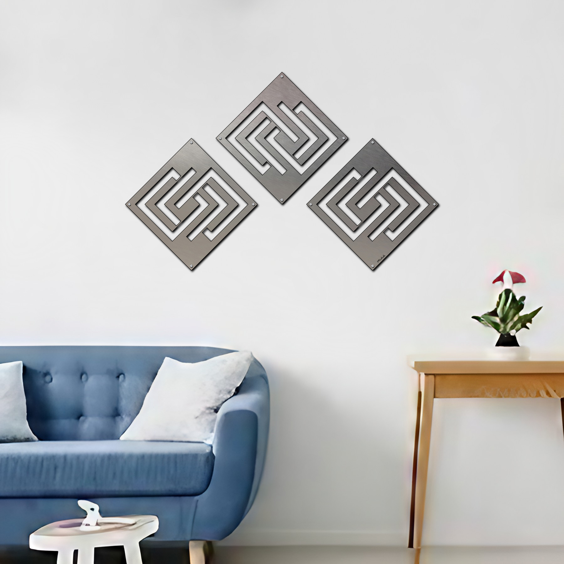 Three abstract diamond wall decorations hang above a blue sofa with cushions and a small plant on a side table.