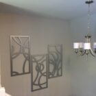 Three decorative metal wall panels and a modern chandelier hang in a well-lit room.