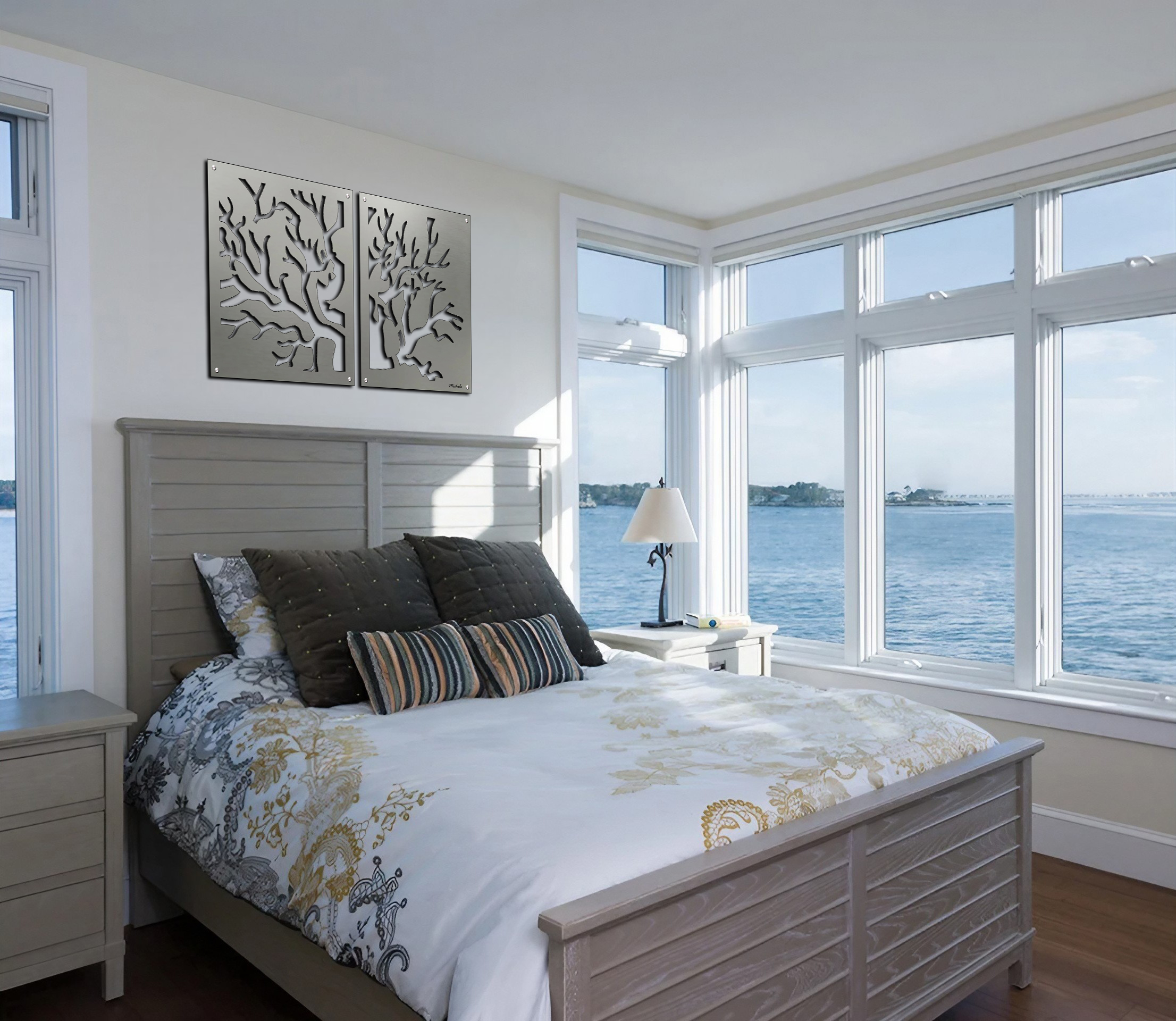 Bright bedroom with a bed, decorative pillows, and large windows overlooking the water. Wall art features tree designs.