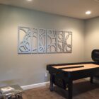 A shuffleboard table with a decorative wall art piece in a cozy room. A small metallic table is nearby.