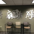 Three metal wall sculptures depict running figures and a cyclist, with empty chairs in the foreground.