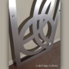 Metal artwork featuring interlocking circular shapes mounted on a wall.