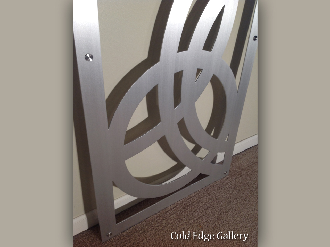 Metal artwork featuring interlocking circular shapes mounted on a wall.