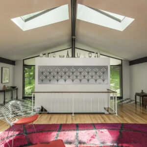A modern living room features a floral wall art piece, skylights, and a colorful rug.
