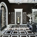 Elegant foyer with black and white checkered floor, decorative wall panels, and a large vase of flowers.