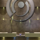 Modern reception area features a large circular metal art piece and a sleek front desk with a "W" logo.