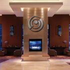 Modern lobby with a central fireplace, decorative wall art, and comfortable seating areas.