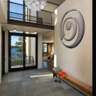 Modern entryway features a large wall art piece, a wooden bench, and natural light from large windows.