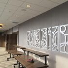 Modern meeting room with decorative wall panels and movable tables. A ladder is visible in the background.