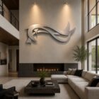 A modern living room features a sleek wall sculpture, a cozy sofa, and a linear fireplace.