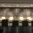 Two light-colored chairs face a textured wall with decorative panels. A small table is nearby.