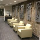 A waiting area with four light-colored chairs against a textured wall and decorative metal panels.