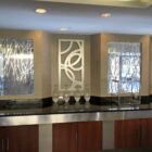 Modern hotel lobby with decorative wall art, glass vases, and a sleek counter. Natural light filters through windows.