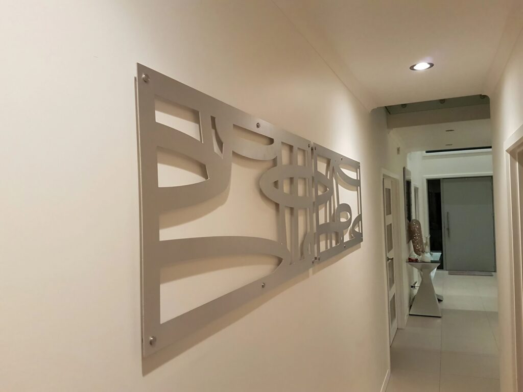 A modern hallway features a decorative metal wall art piece and a side table with an object.