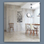 Minimalist dining area with a wooden table, white chairs, a clock on the wall, and contemporary art. Neutral tones and natural light create a serene atmosphere. Cold Edge Gallery text on the right.