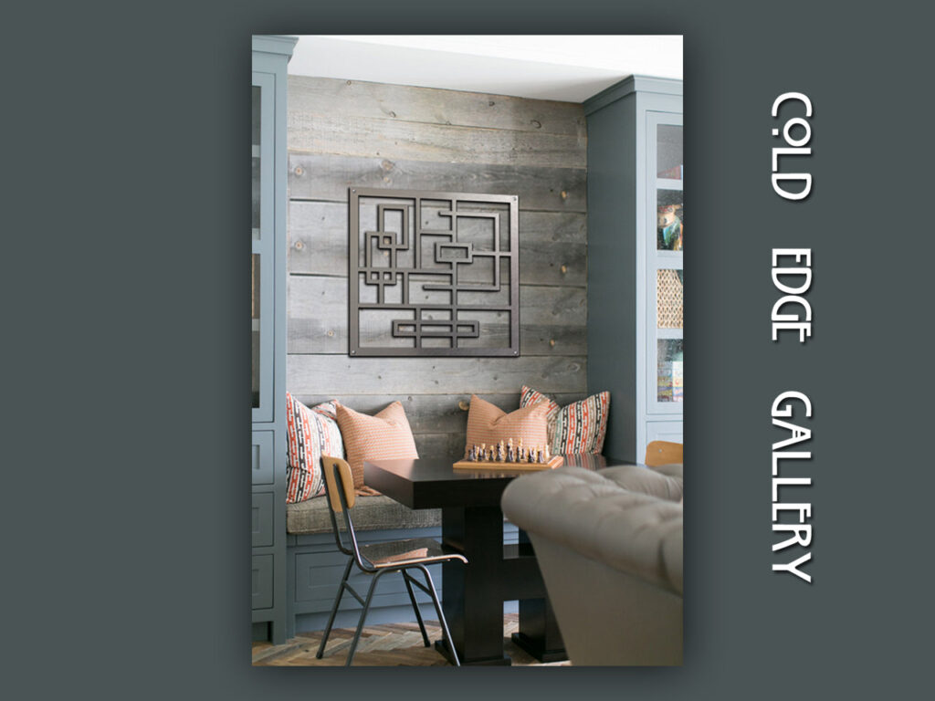 A modern interior features a geometric wall art piece above a table with chairs and decorative pillows.