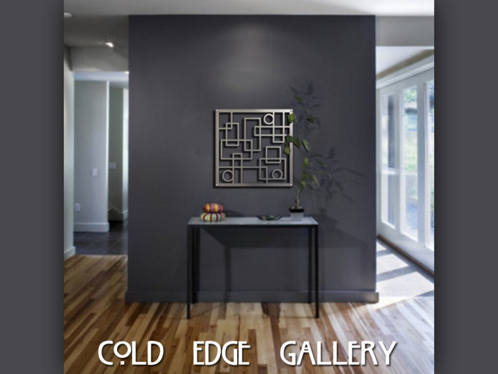 A modern art piece hangs on a dark wall above a table with a plant and decorative items.