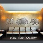 A waiting area with gray chairs and wall art featuring abstract figures and the text "COLD EDGE GALLERY.