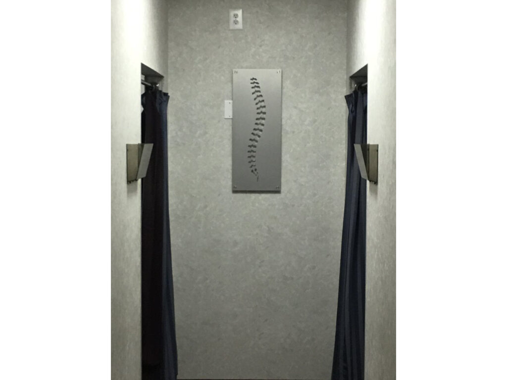 A hallway with two dark curtains and a spine artwork on the wall.