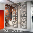 A person walking by a modern indoor space featuring custom metal partitions with curved patterns and the text "Cold Edge Gallery" on the lower part of the image.