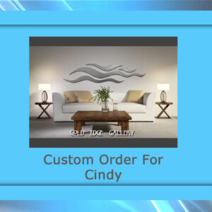 An artistic metal wall piece featuring a circular arrangement of delicate metal strands, creating a sunburst effect. The metallic finish contrasts beautifully with the deep-colored background.