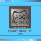 A framed metal artwork featuring a tooth design and the text "ADC Welcome to the family." Below, "Custom Order For Levi" on a light blue background.