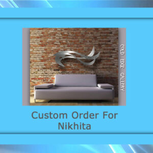 A modern gray sofa is placed against a brick wall with sleek, abstract metallic artwork above it. The text reads "Custom Order For Nikhita" with "Cold Edge Gallery" on the side.