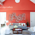 A modern living room with red walls, white ceiling, and contemporary furniture. Decorative white geometric panels hang on the wall with text "Cold Edge Gallery" in the upper left corner.