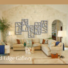 Spacious living room with beige sectional sofa, abstract metal wall art, potted plants, and modern decor. Labeled "Cold Edge Gallery.