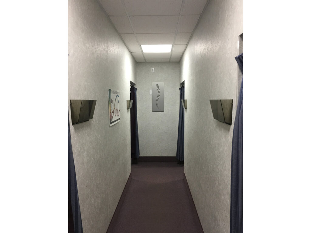 Narrow hallway with gray walls, curtains on either side, and a wall-mounted sign.