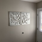 Metal artwork of tree branches displayed on a beige wall near a door with a window.