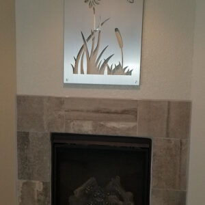 Metal wall art of a flower and hummingbird above a modern fireplace with stone surround.