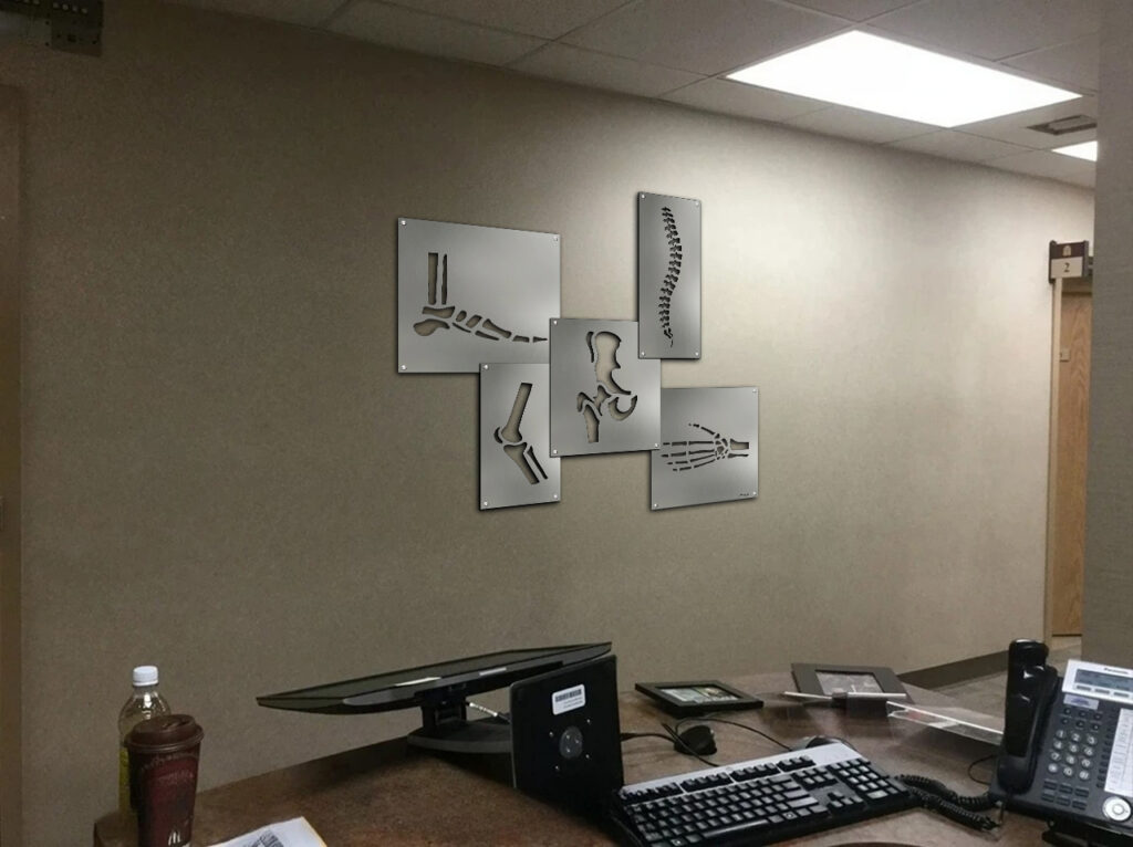 X-ray displays of bones and joints mounted on a wall near a desk with a computer and phone.